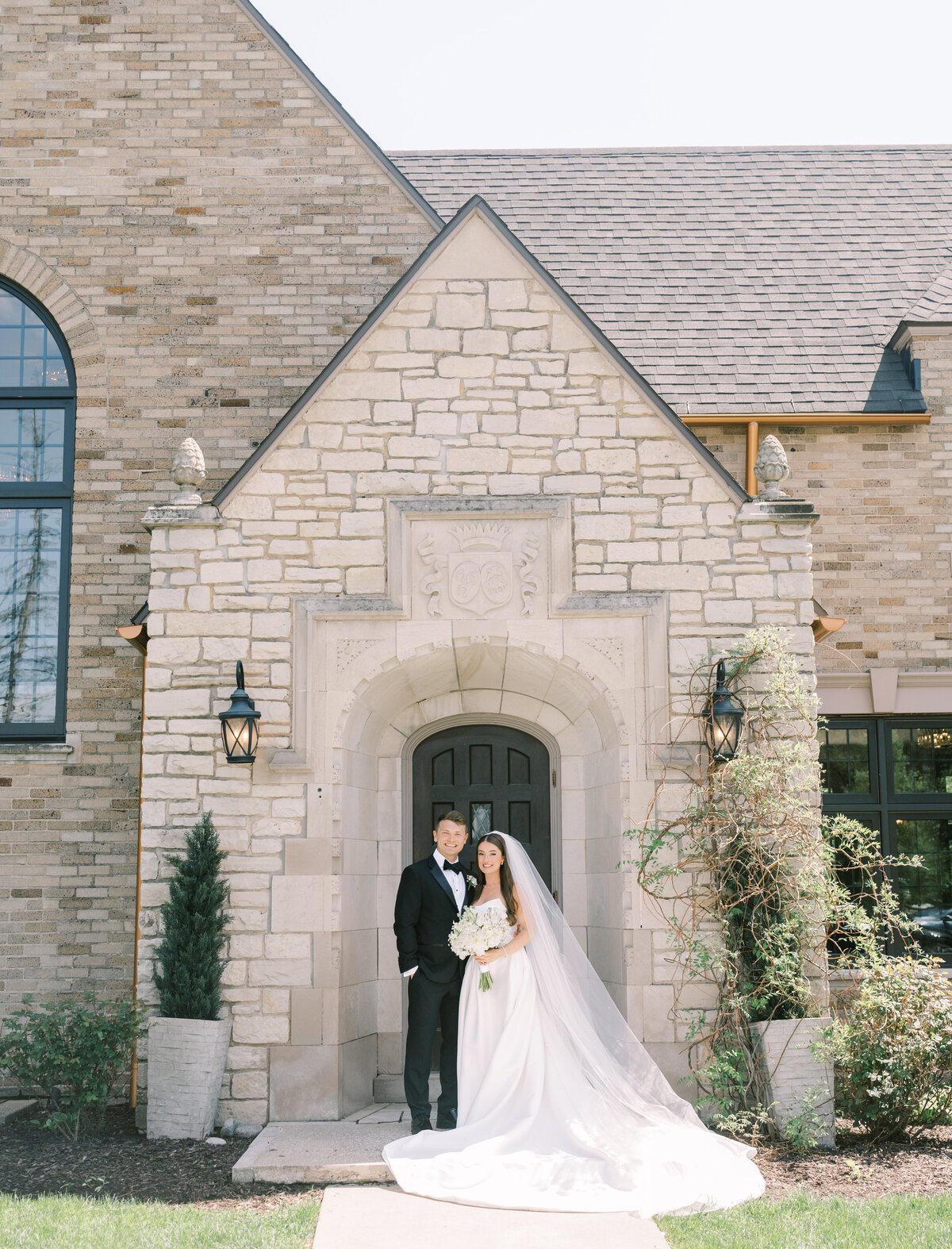 A newly married couple stands in a arched stone doorway of a old manor in Grand Rapids at their wedding at Venue3Two