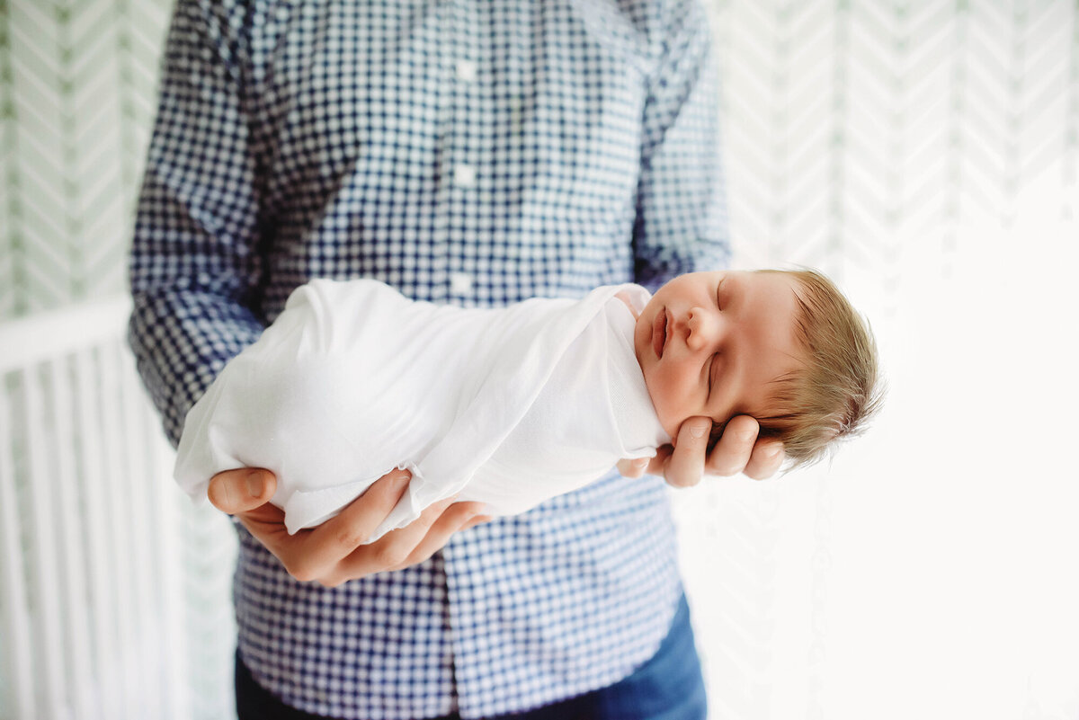 Charleston’s #1 Lifestyle Newborn Photographer, father holding her infant for Newborn Photoshoot in Charleston, SC.