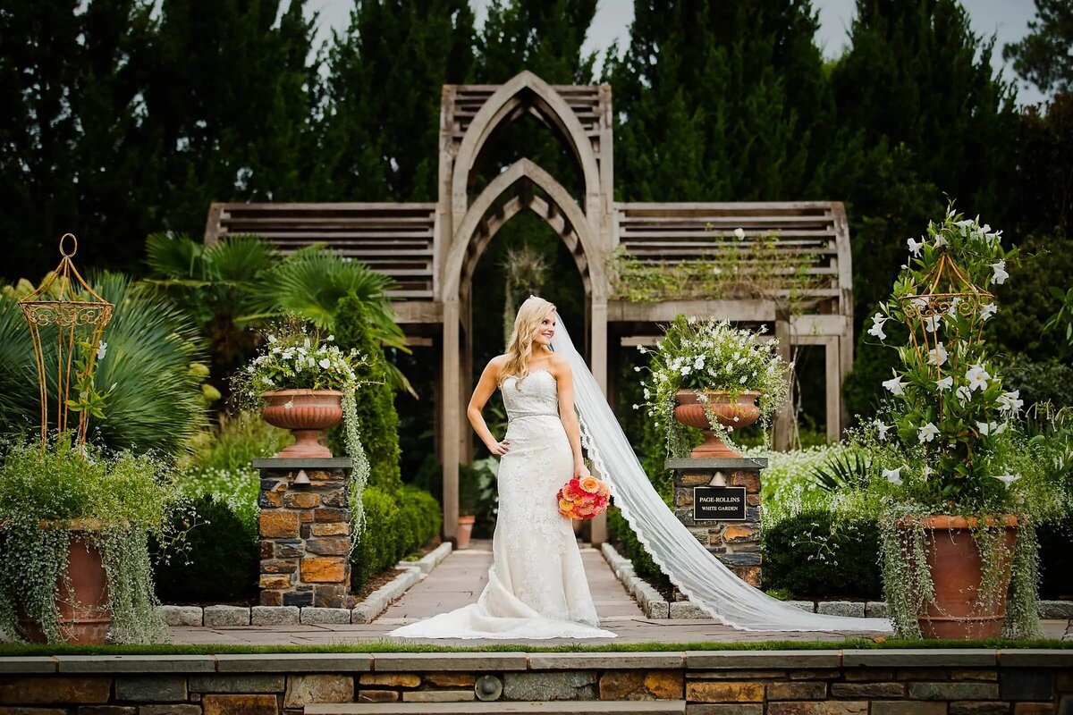 A bride holding a bouquet while standing in a small garden area