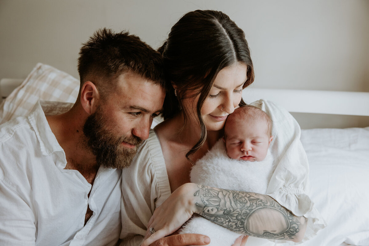 Mum and dad cuddle close with newborn  baby