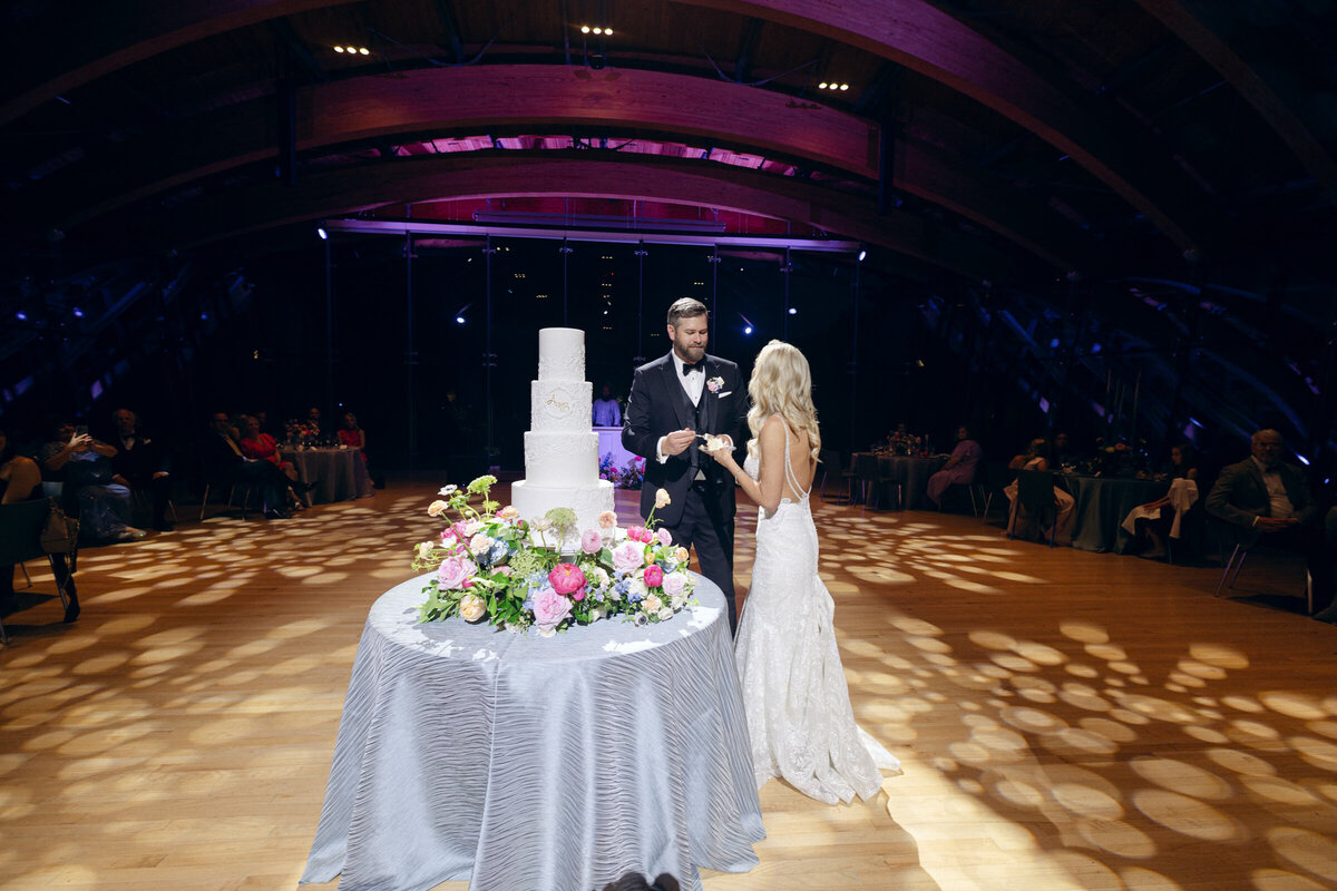 A wedding day photo of the bride and groom cutting their wedding cake at Crystal Bridges Museum of American Art