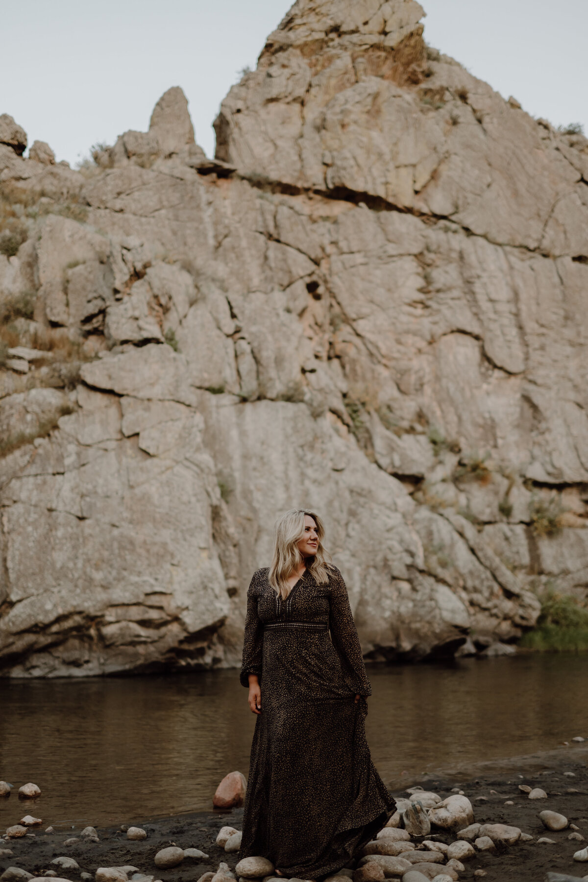 Jessica of Your Modern Story standing in river with black dress and large mountan in the background