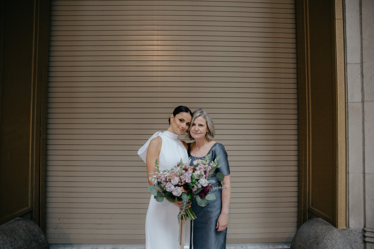 Bride and Mother of the Bride stand in front of gold colored garage doors during downtown Chicago wedding portraits