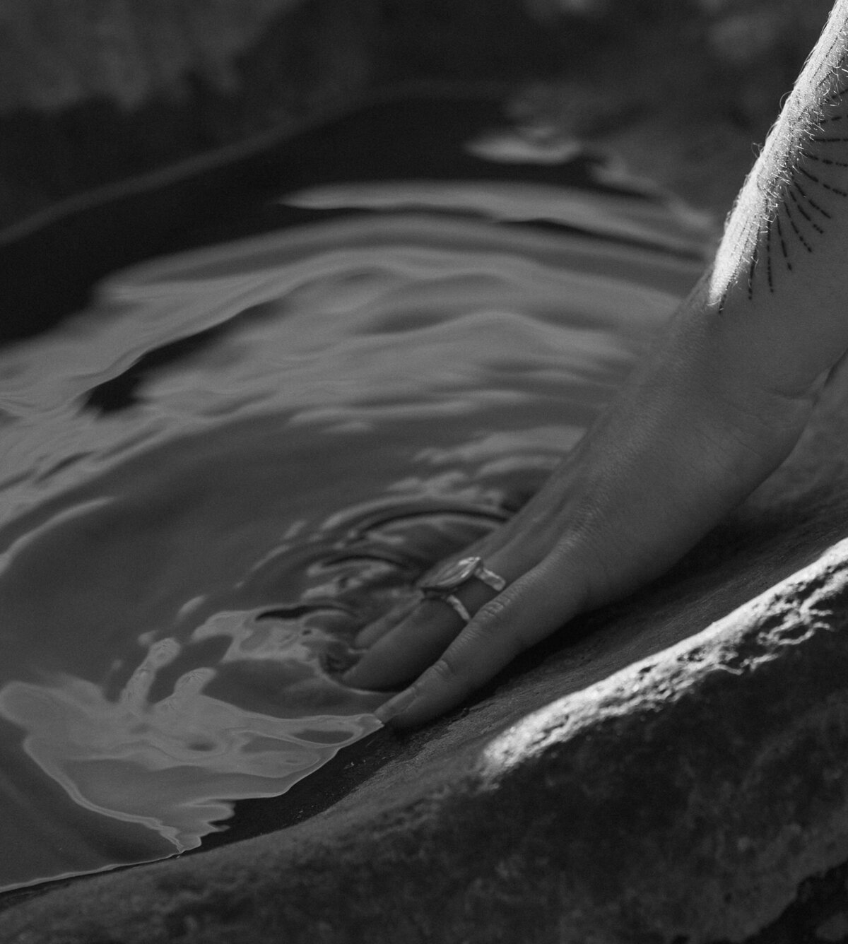 artistic close up of a woman's hand touching the water