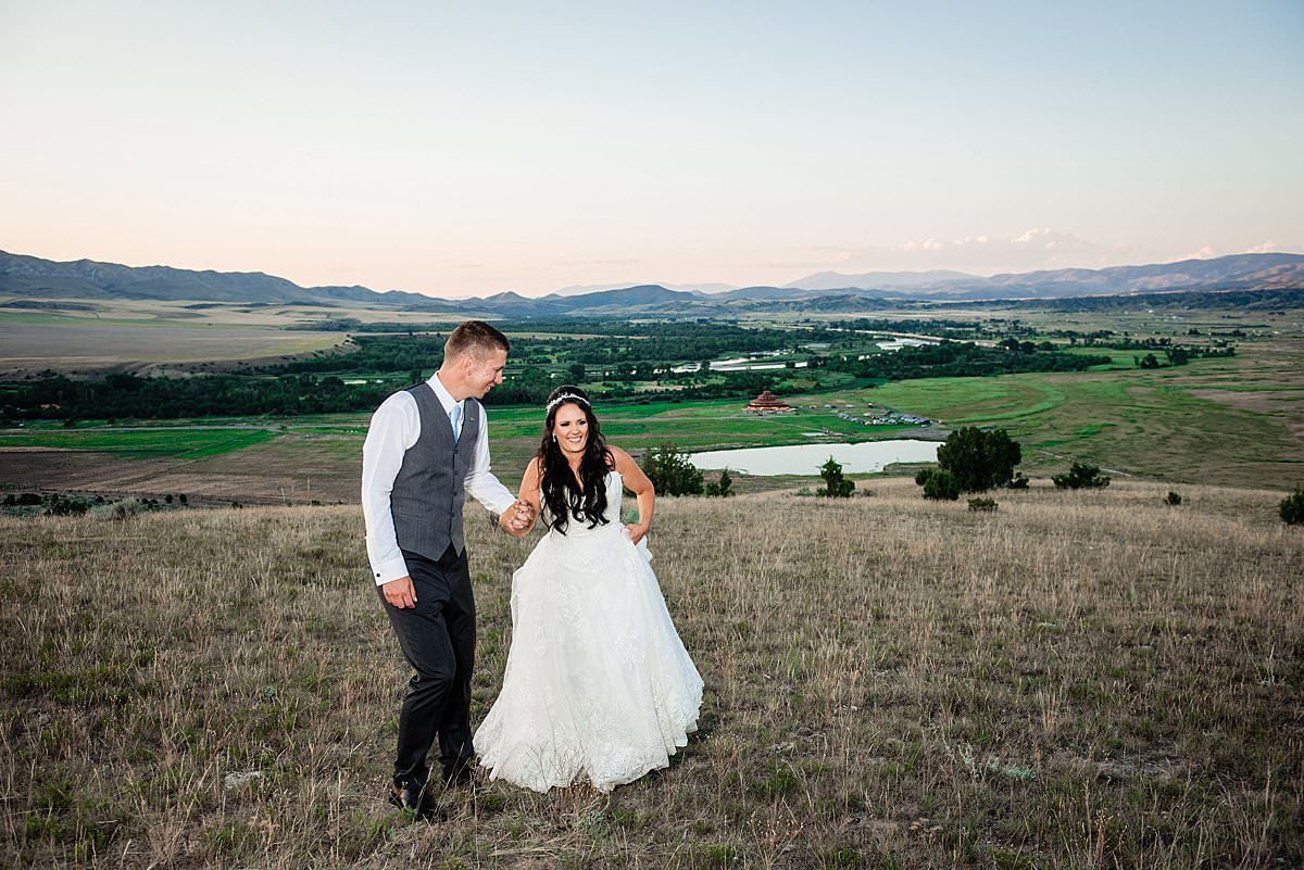Bride and groom strolling together in the Montana mountainside