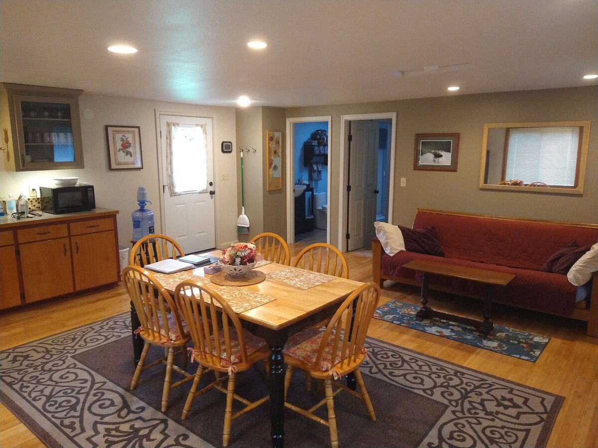 Dining table, kitchen counter and couch shown in open living area of cottage.