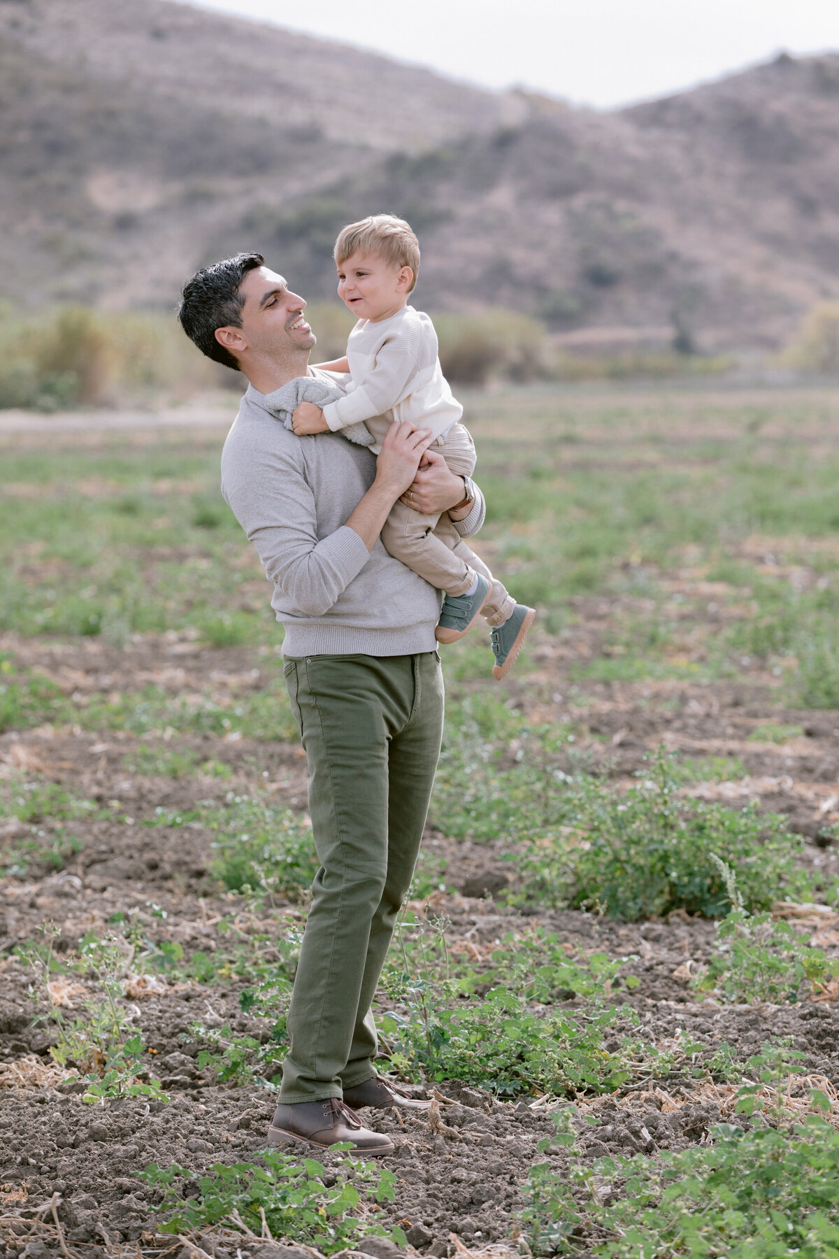 A dad holding their child and smiling at them