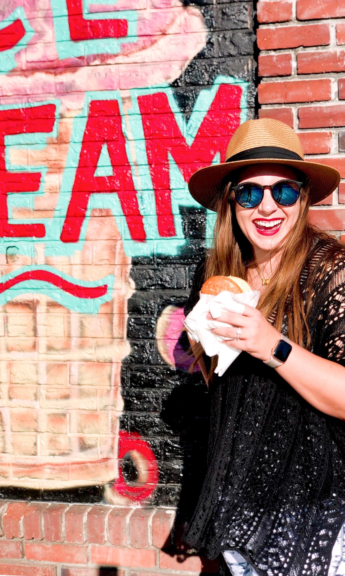 A girl eats an ice cream donut sandwich in the summer sun