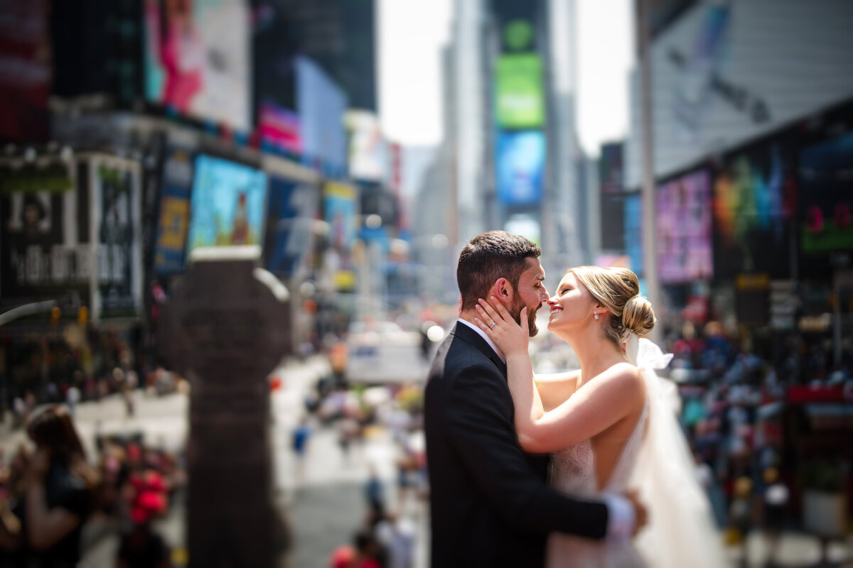 A bride and groom about to kiss while standing in a busy city center.