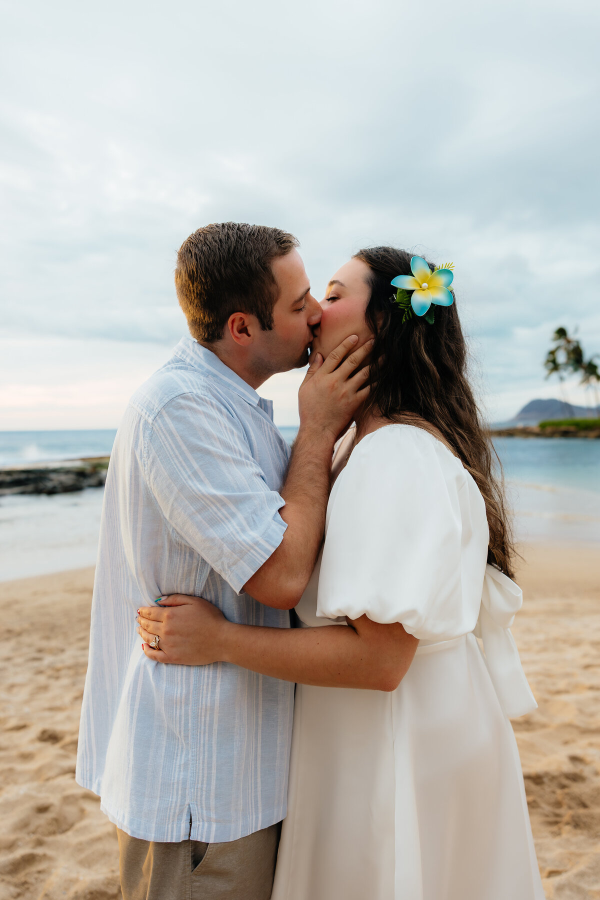 Couple sharing a kiss on the beach in Oahu during their sunset photoshoot in Ko Oolina