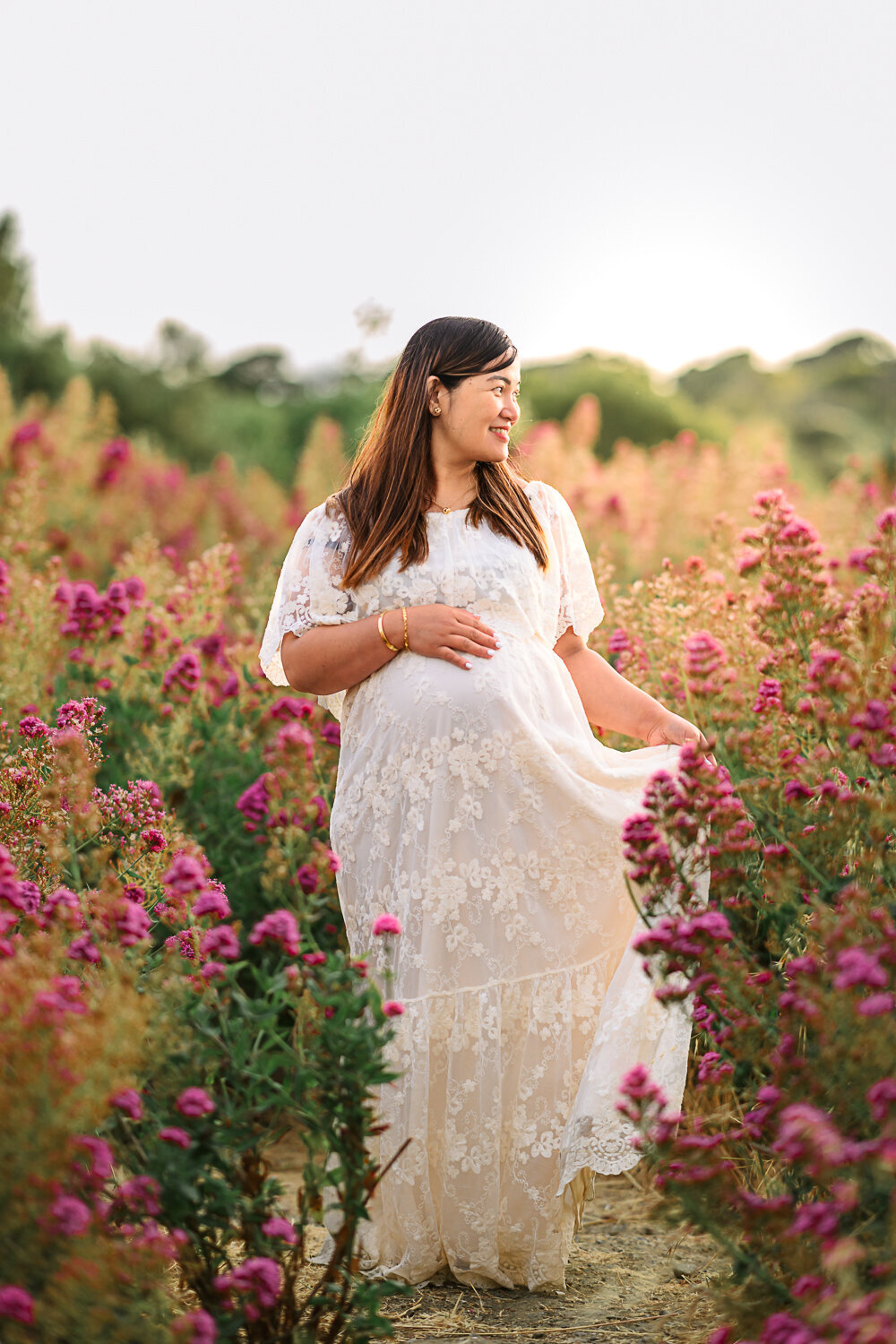 mom in white maternity dress standing in purple wildflowers near lafayette