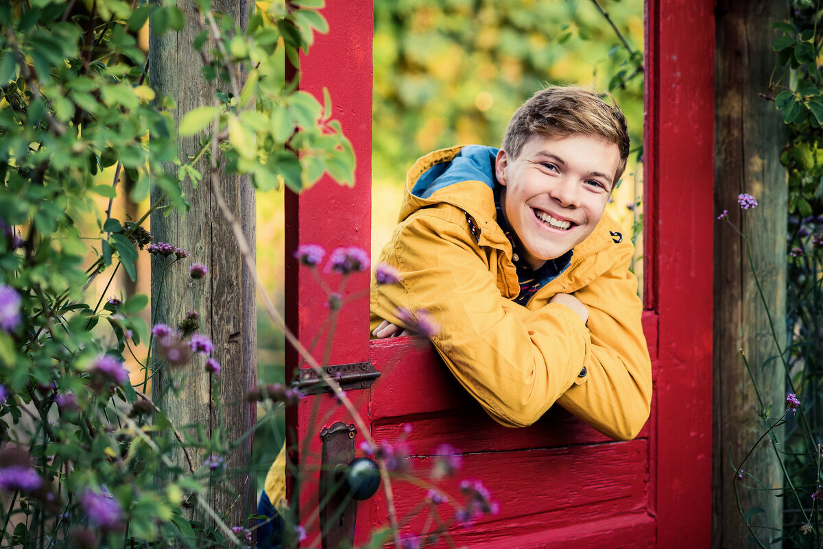 senior boy leaning on red door
