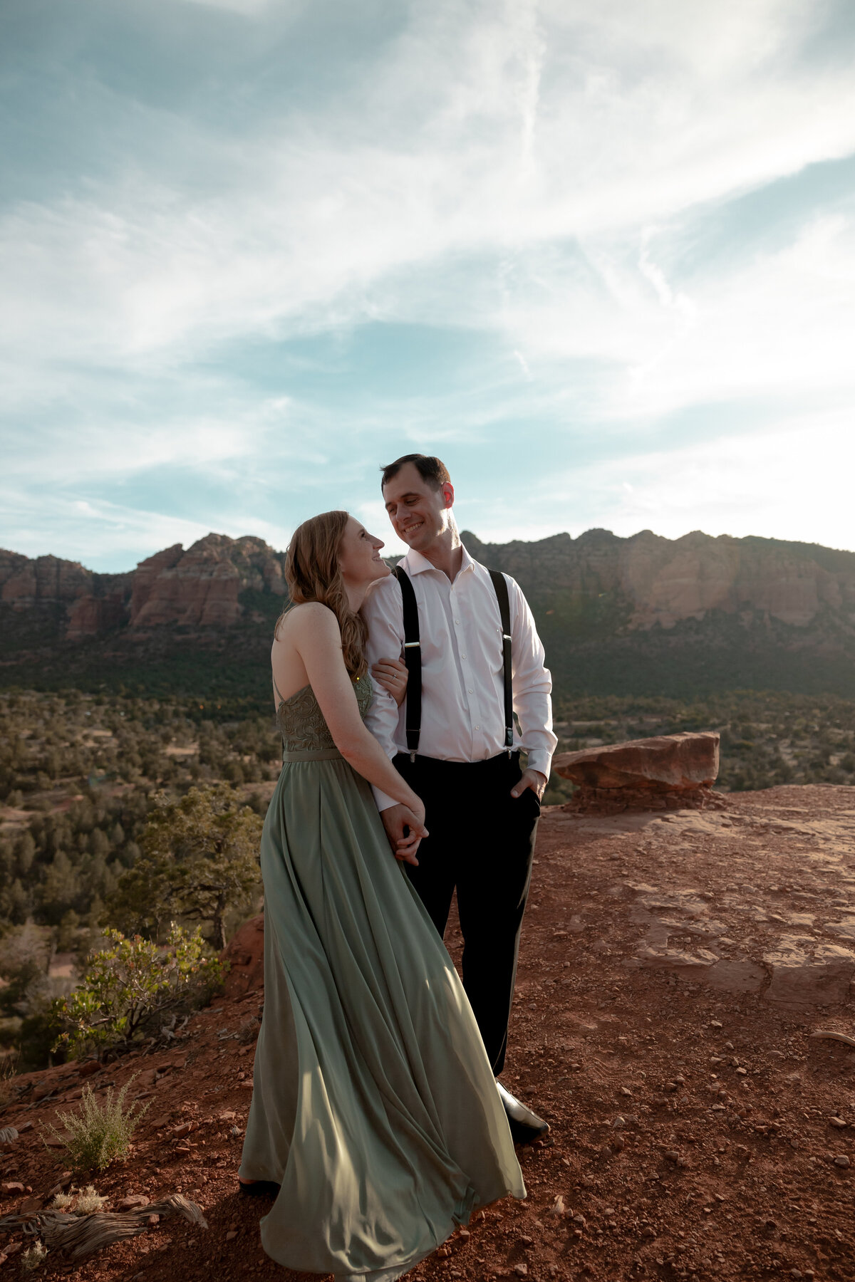 Couple standing against red rock backdrop during Sedona engagement session