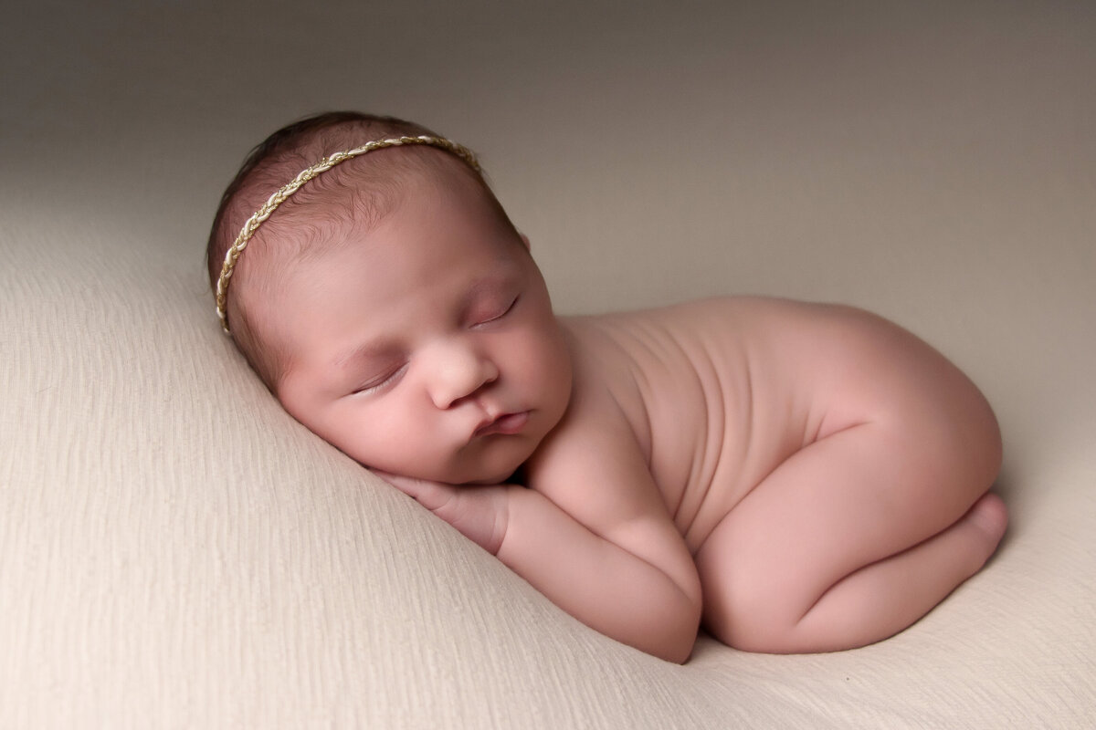 baby girl posing on a neutral backdrop during her newborn session