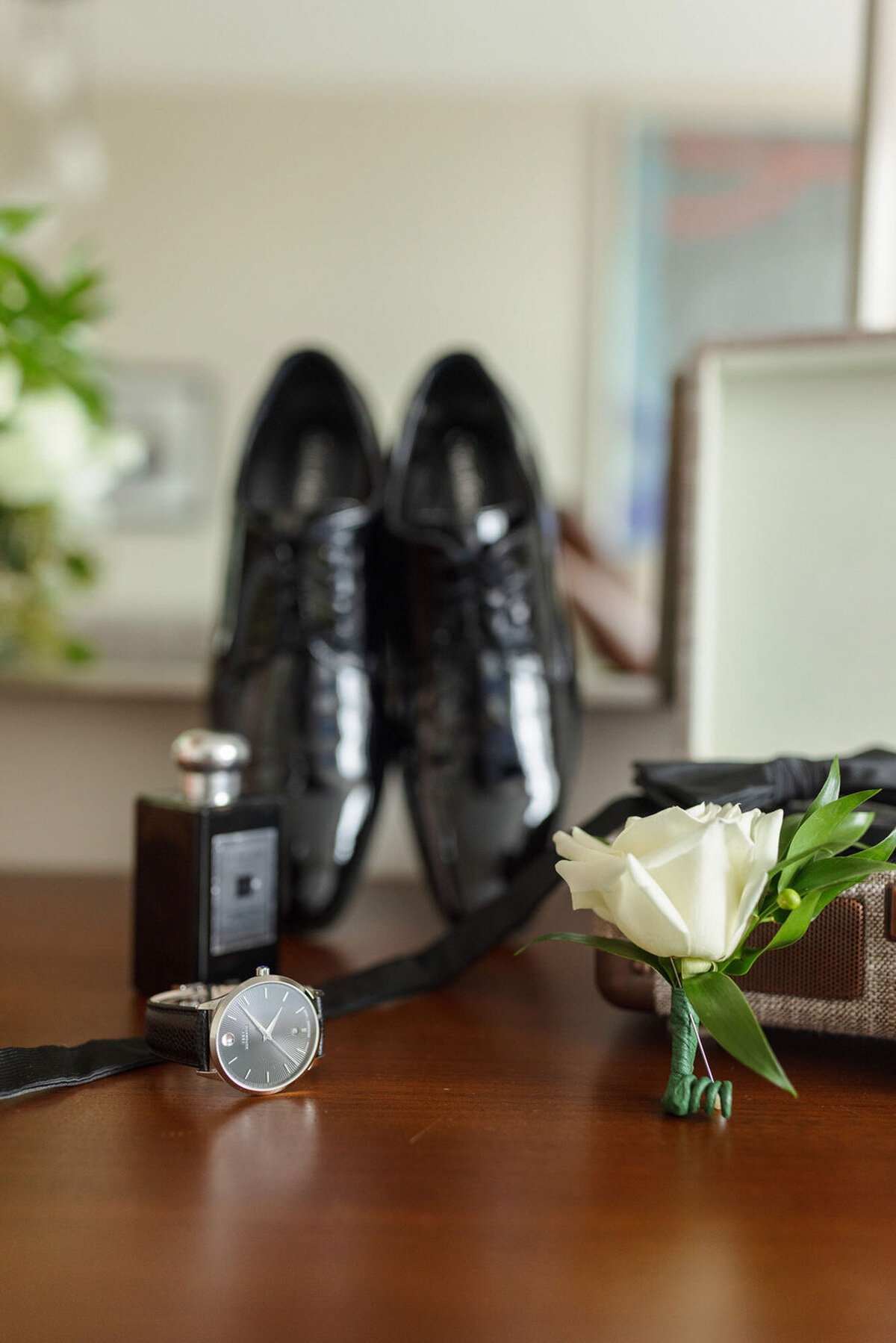 groom's details with rose, cologne, watch, and shoes