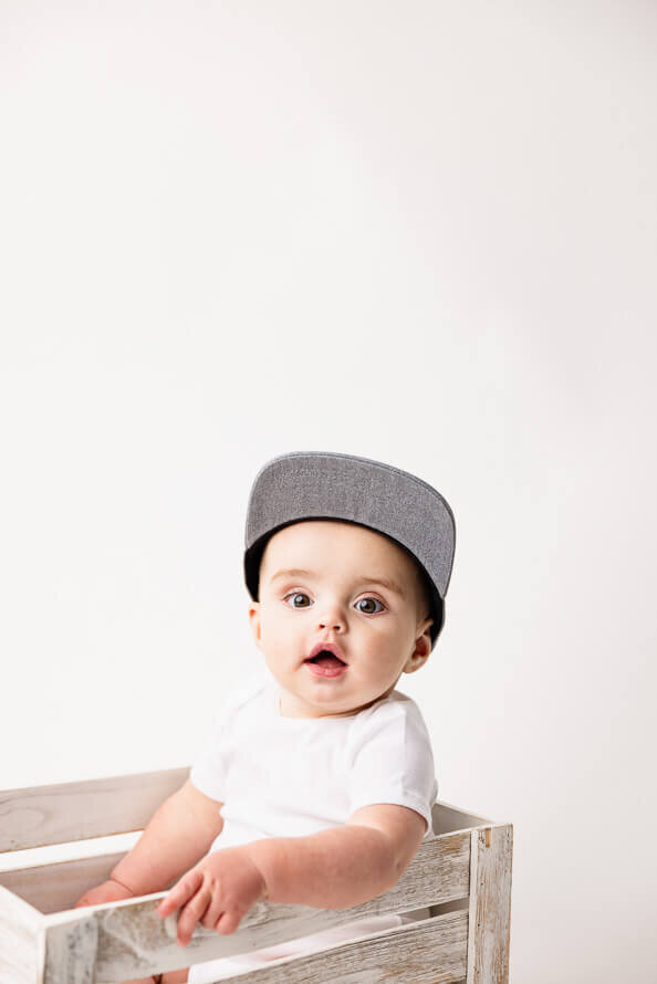 Baby boy in hat looks at camera.