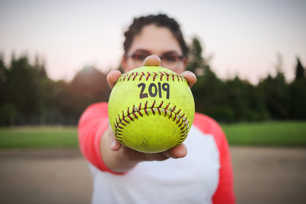 Close up of a girl holding a softball for her senior pictures in Olympia WA
