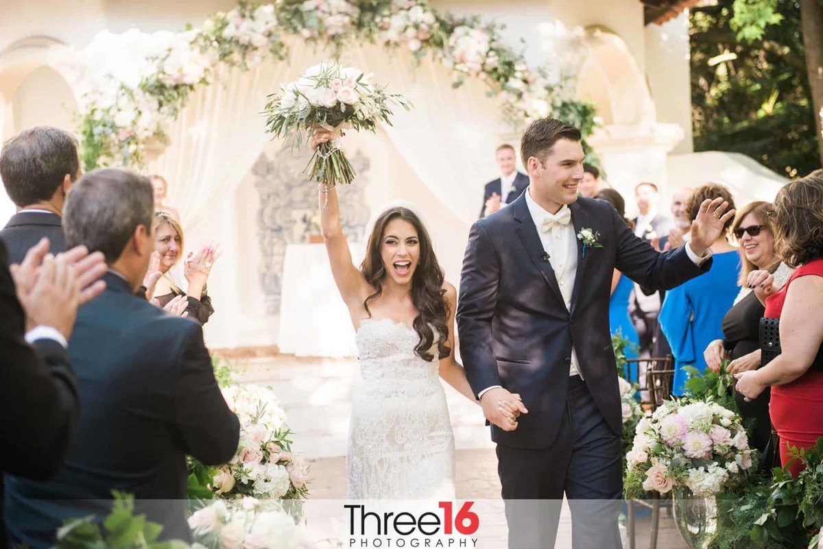 Newly married couple walk down the aisle acknowledging their guests