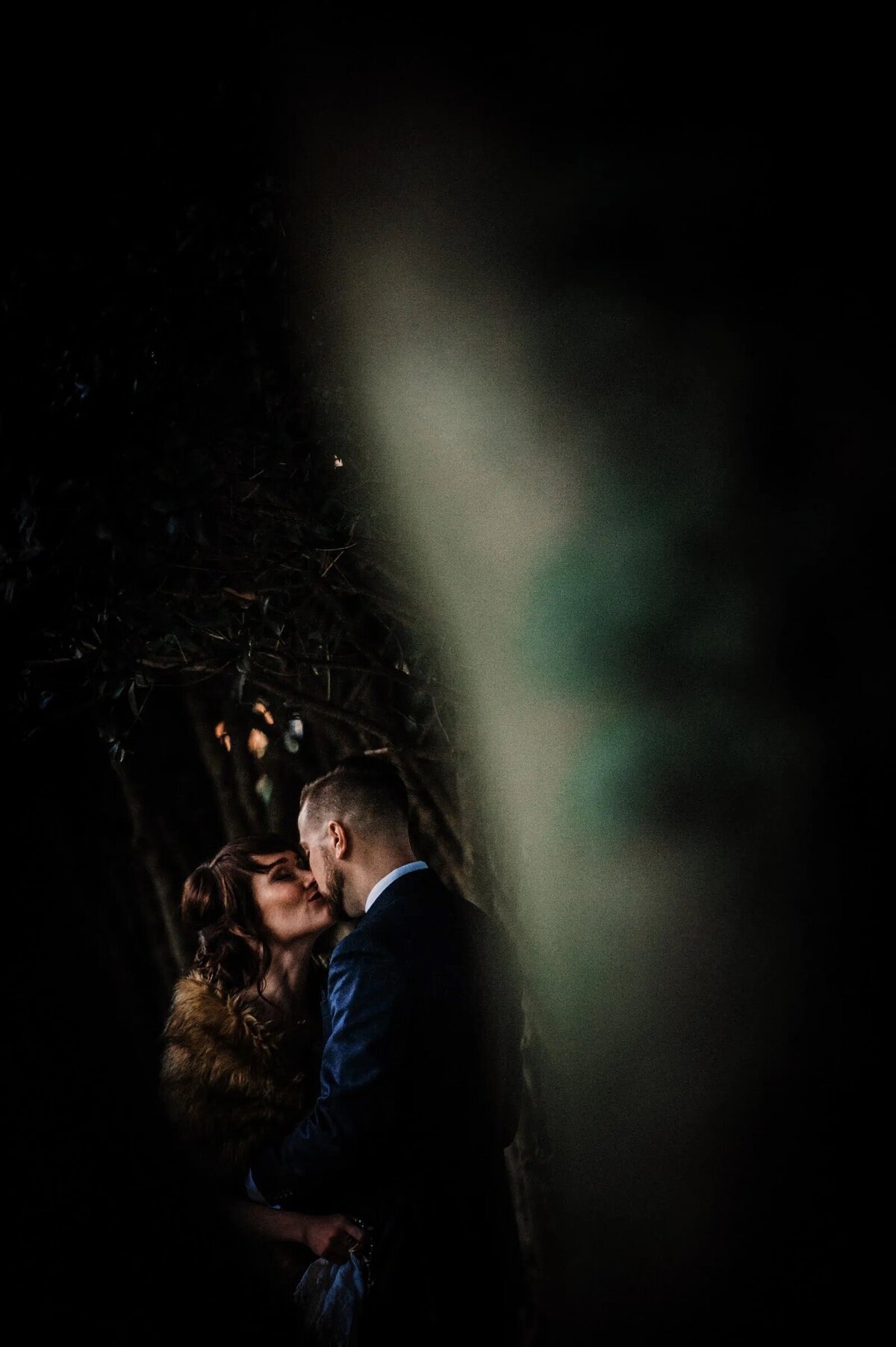 A bride and groom kissing in darkness.