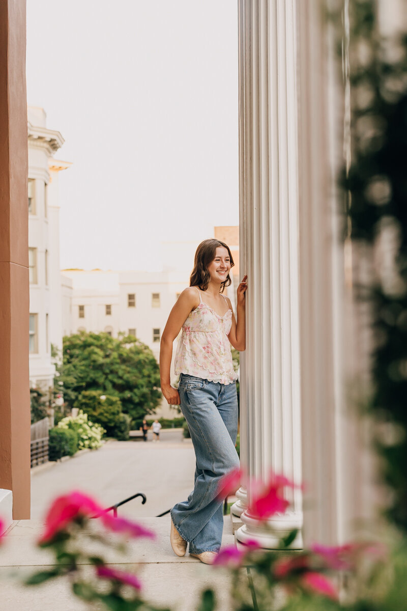 Senior leaning against a column at Belmont Mansion, looking into the distance.