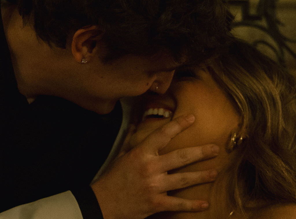 A newlywed couple smiling and about to kiss.