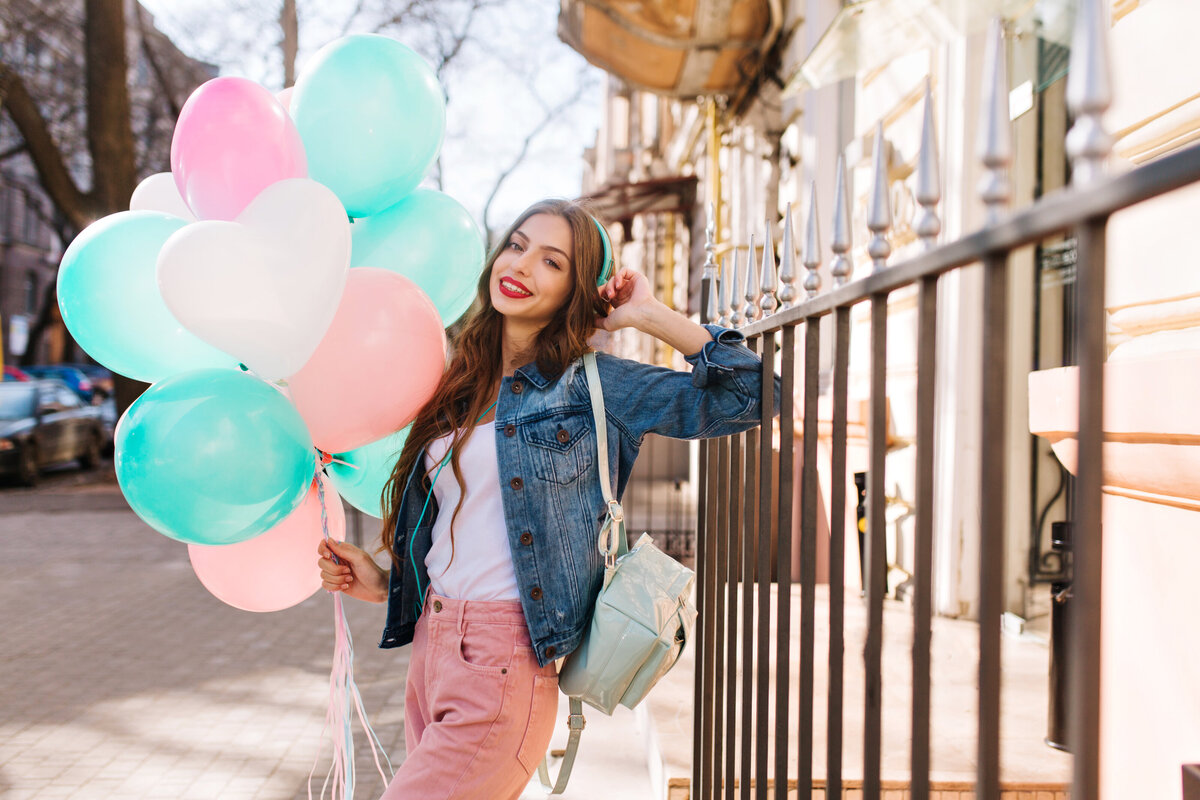 portrait-smiling-young-woman-wearing-denim-jacket-stylish-pants-posing-with-birthday-balloons