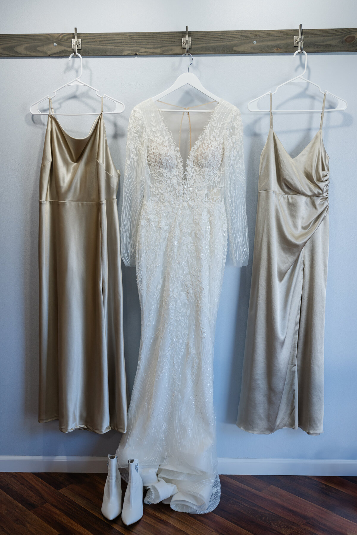 wedding dress and bridesmaids dress on hangers in bridal suite white and champagne