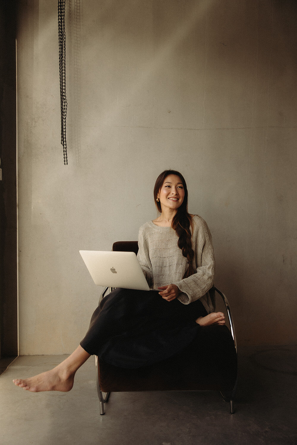 Natural light branding photography of a nutritionist  entrepreneur working in a cozy  studio with a laptop