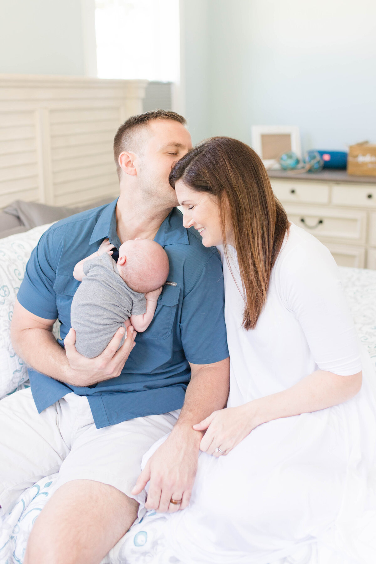 husband kissing his wife's head at lifestyle newborn family session