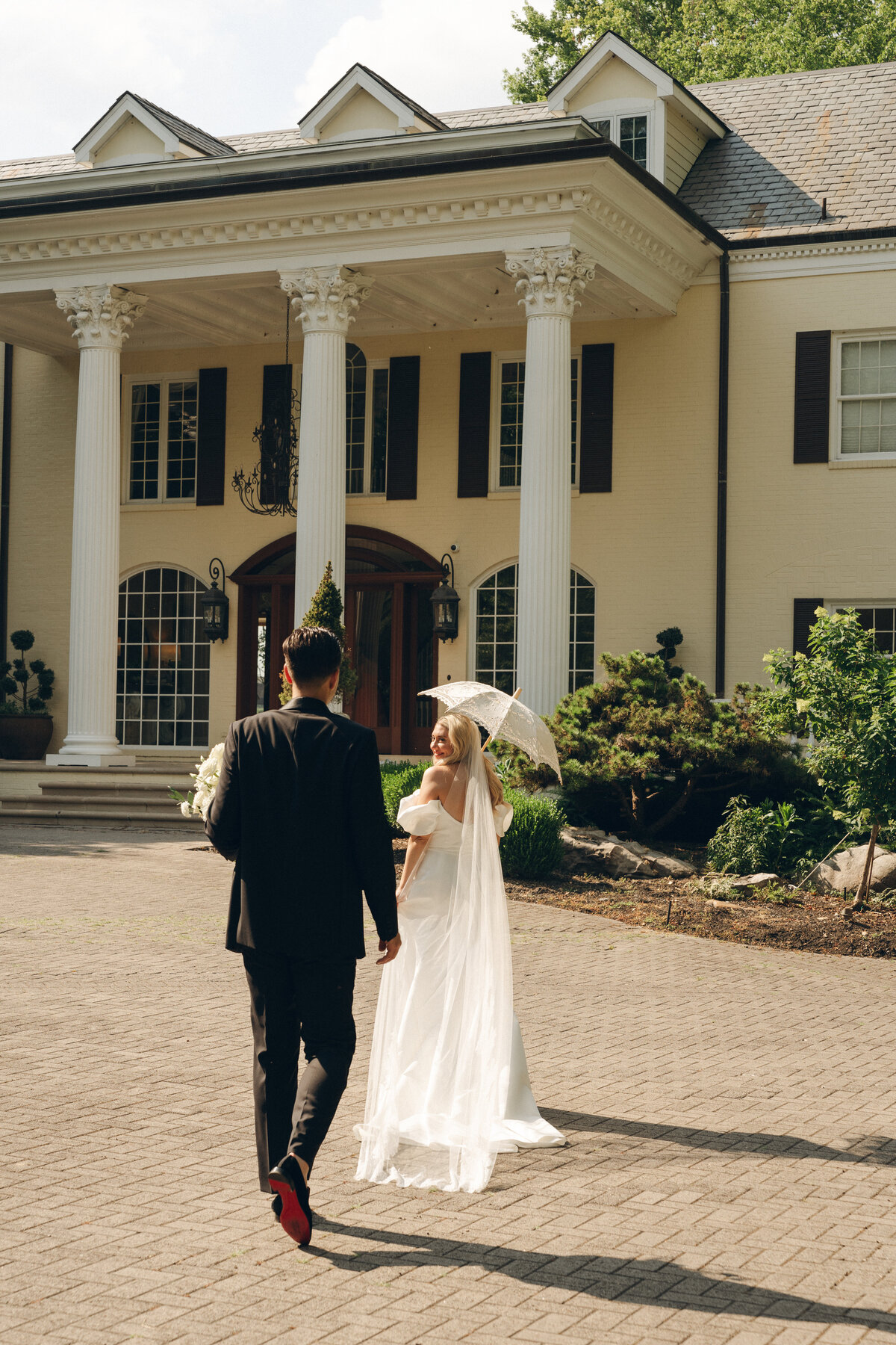 A bride and groom walking towards a yellow mansion in Nashville wearing Christian Louboutins.
