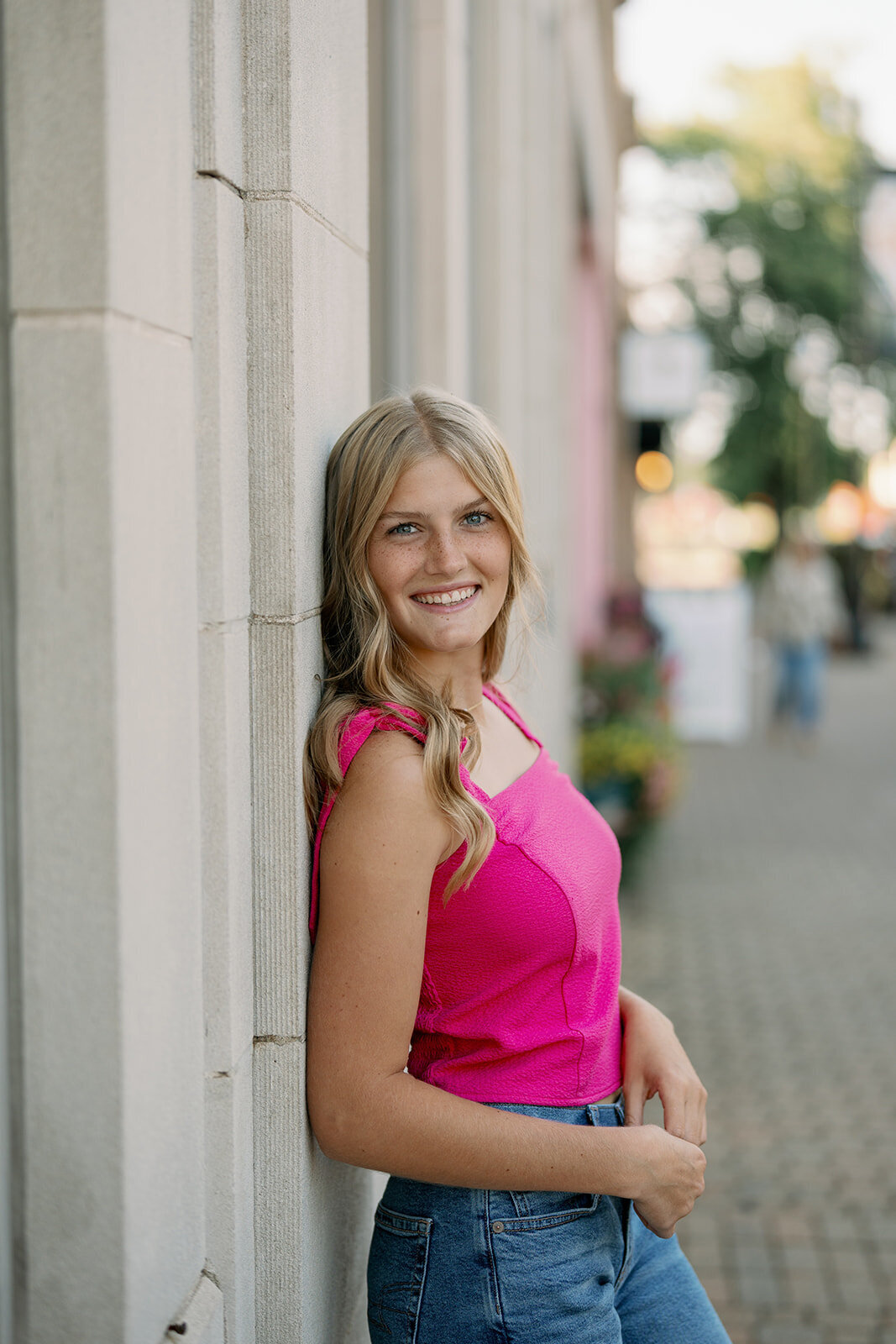 Senior girl leaning against a stone wall in downtown Holland, Michigan during her urban senior photo session.
