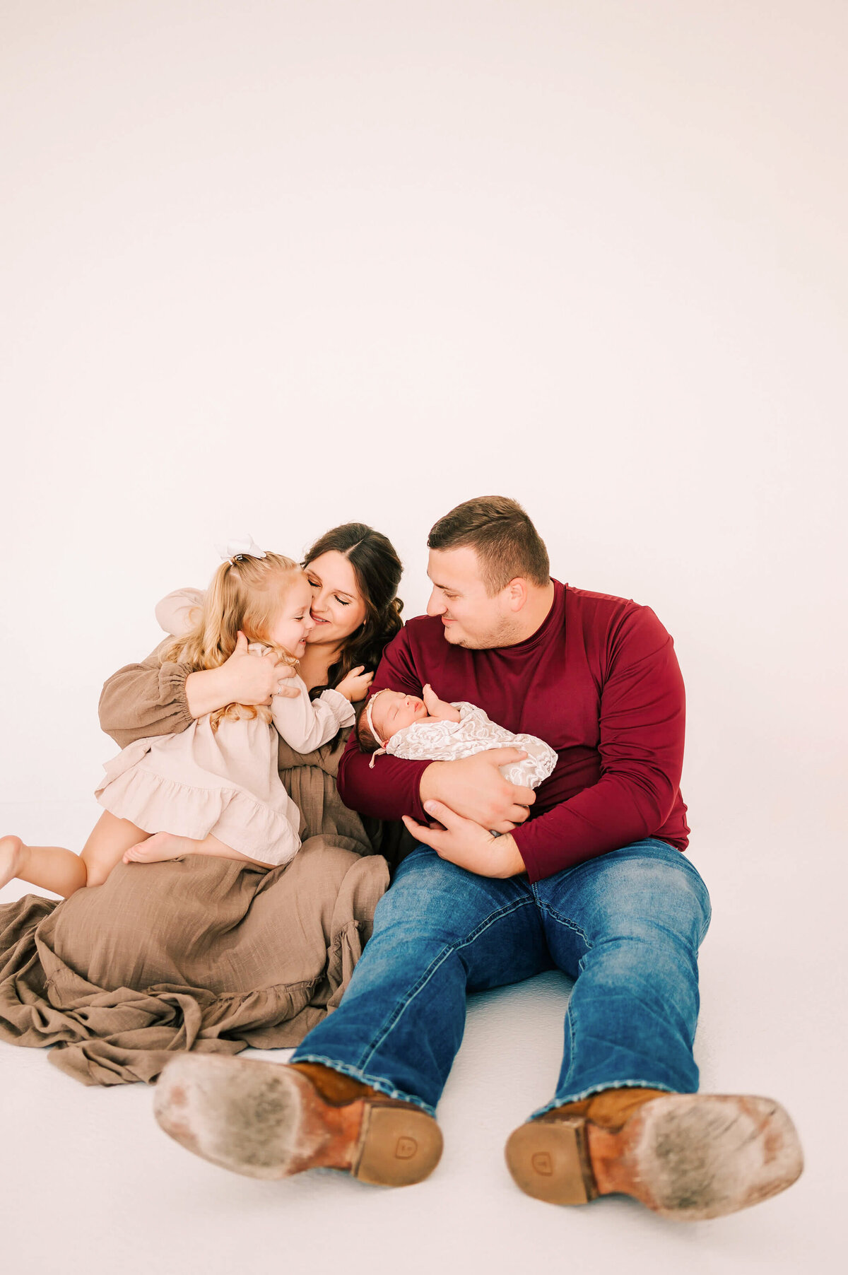 family of 4 hugging while sitting on floor during Springfield Mo newborn photogrpahy session