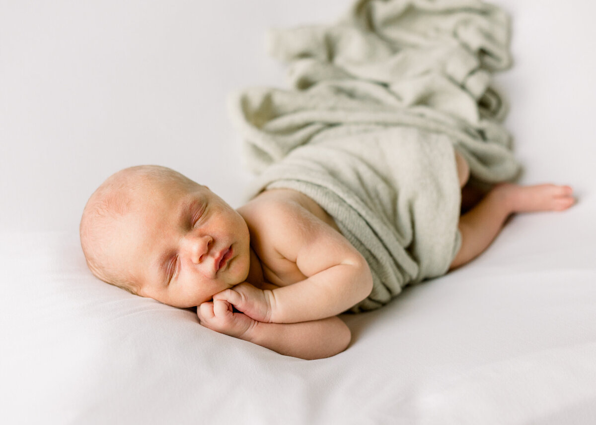 Newborn baby boy on beanbag with sage green wrap in studio.  Image taken by Brandon, MS studio newborn photographer.