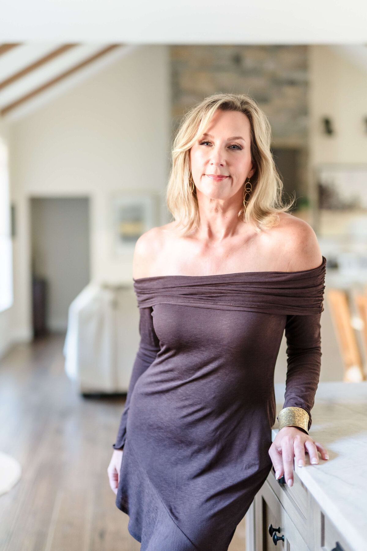 professional woman wearing brown dress standing in modern kitchen for creative headshot