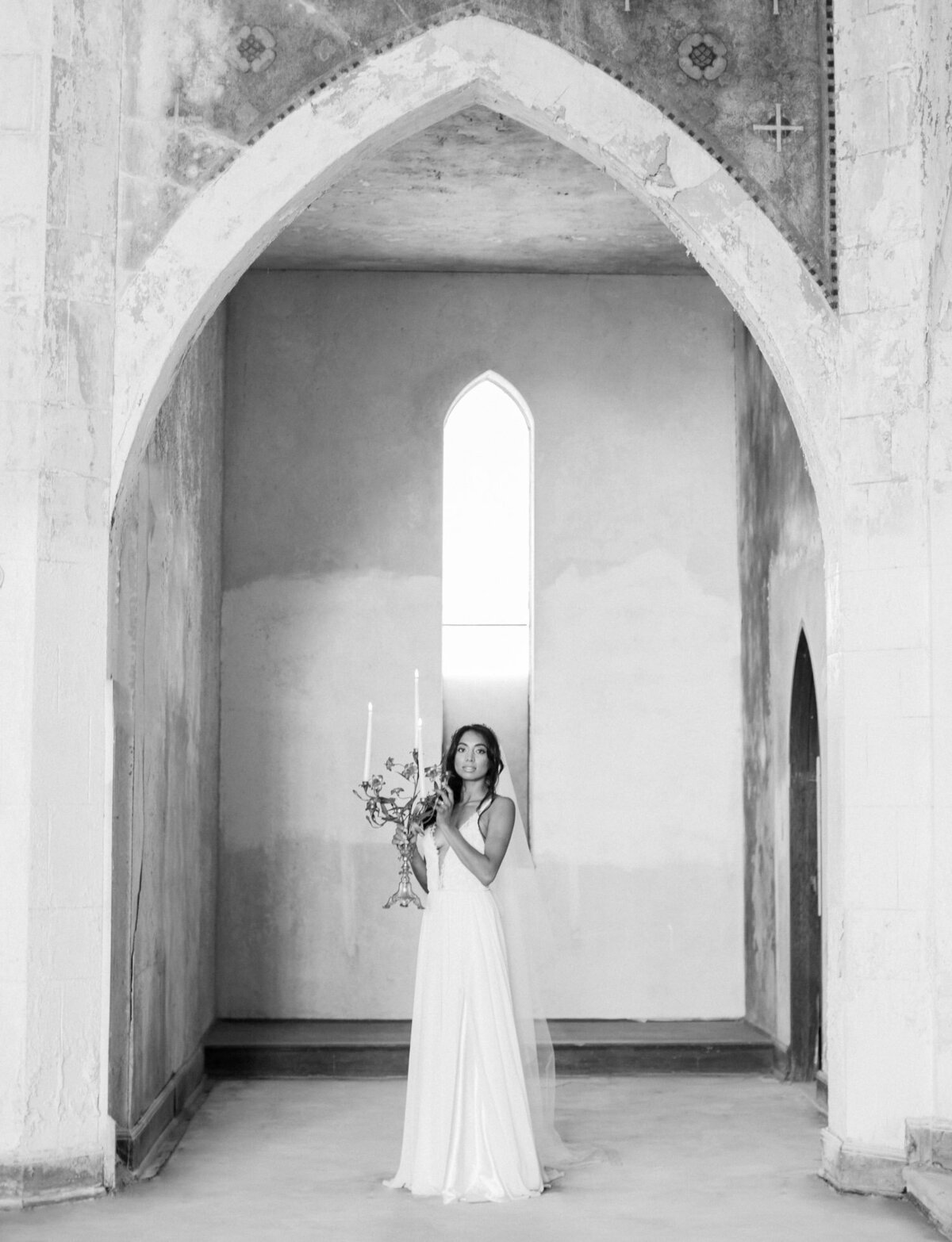 bride with candelabra, crumbling arches of abandoned cathedral, ruins wedding venue