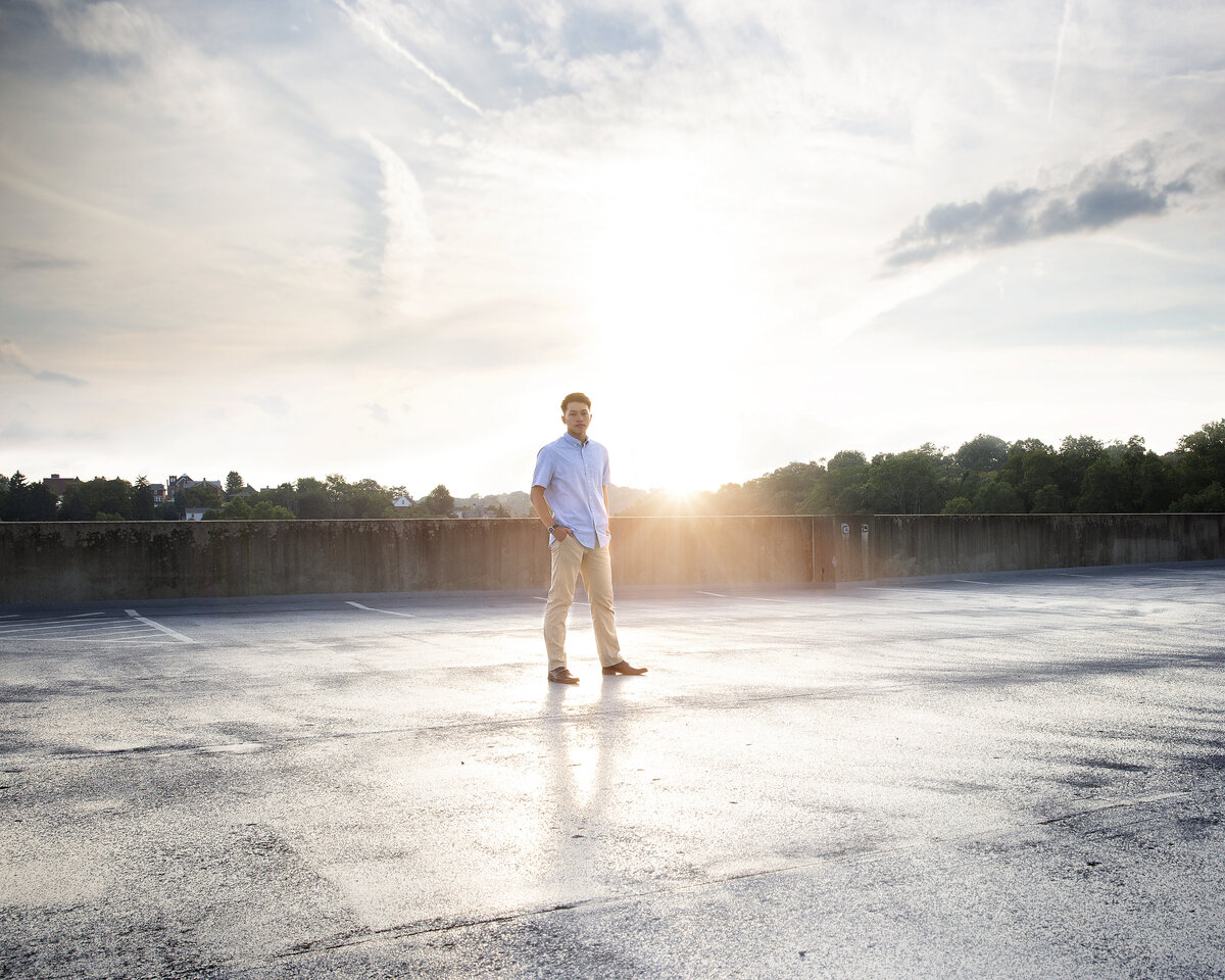 Latrobe High school senior poses with hands in pockets at sunset on garage deck for senior portraits in Greensburg.