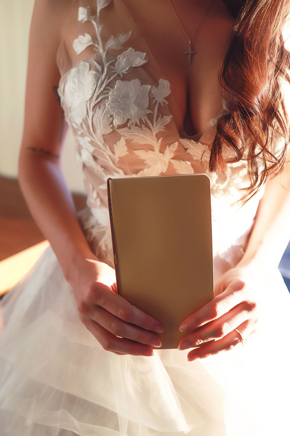 A bride holding her vows book close to her before she gets married.