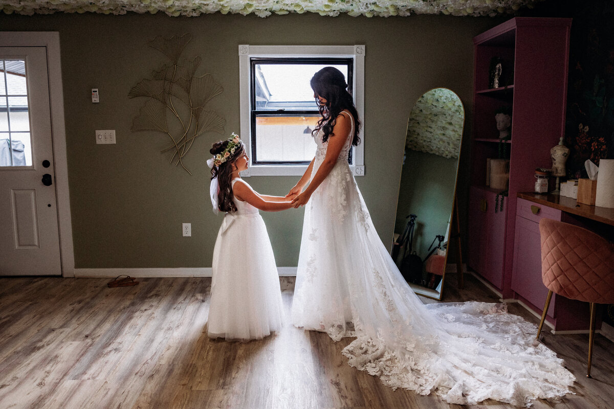 Shannon Lee, from Love Like Wild Photography, captures a tender moment between a bride and a young flower girl holding hands before the ceremony.
