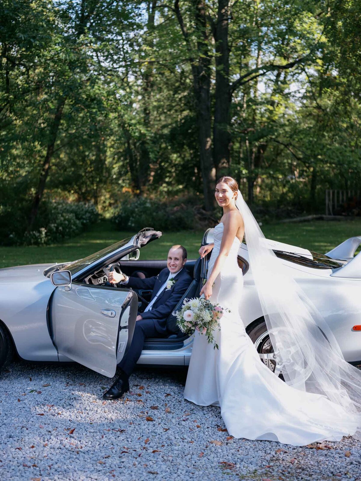 Bride and groom beside their favorite sports car on their wedding day.