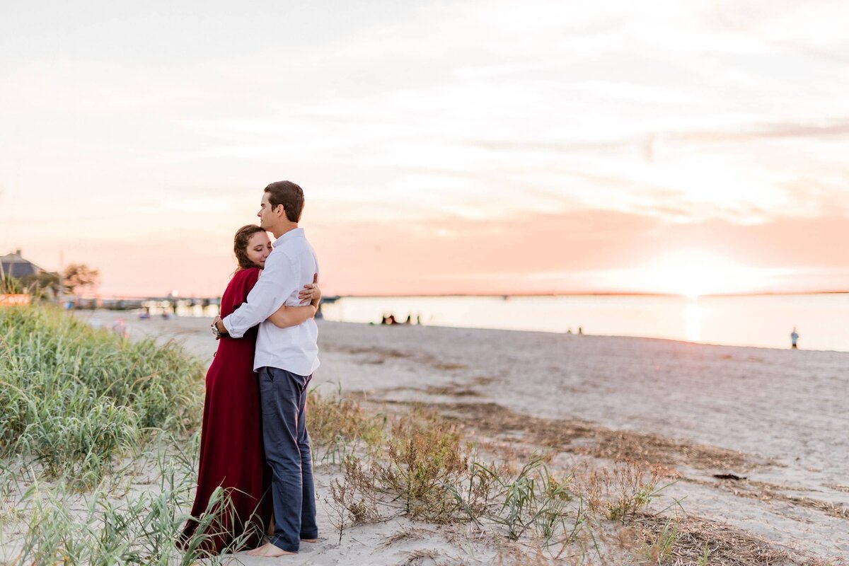 Couple hugging at the beach in Ocean City with the sunset behind them