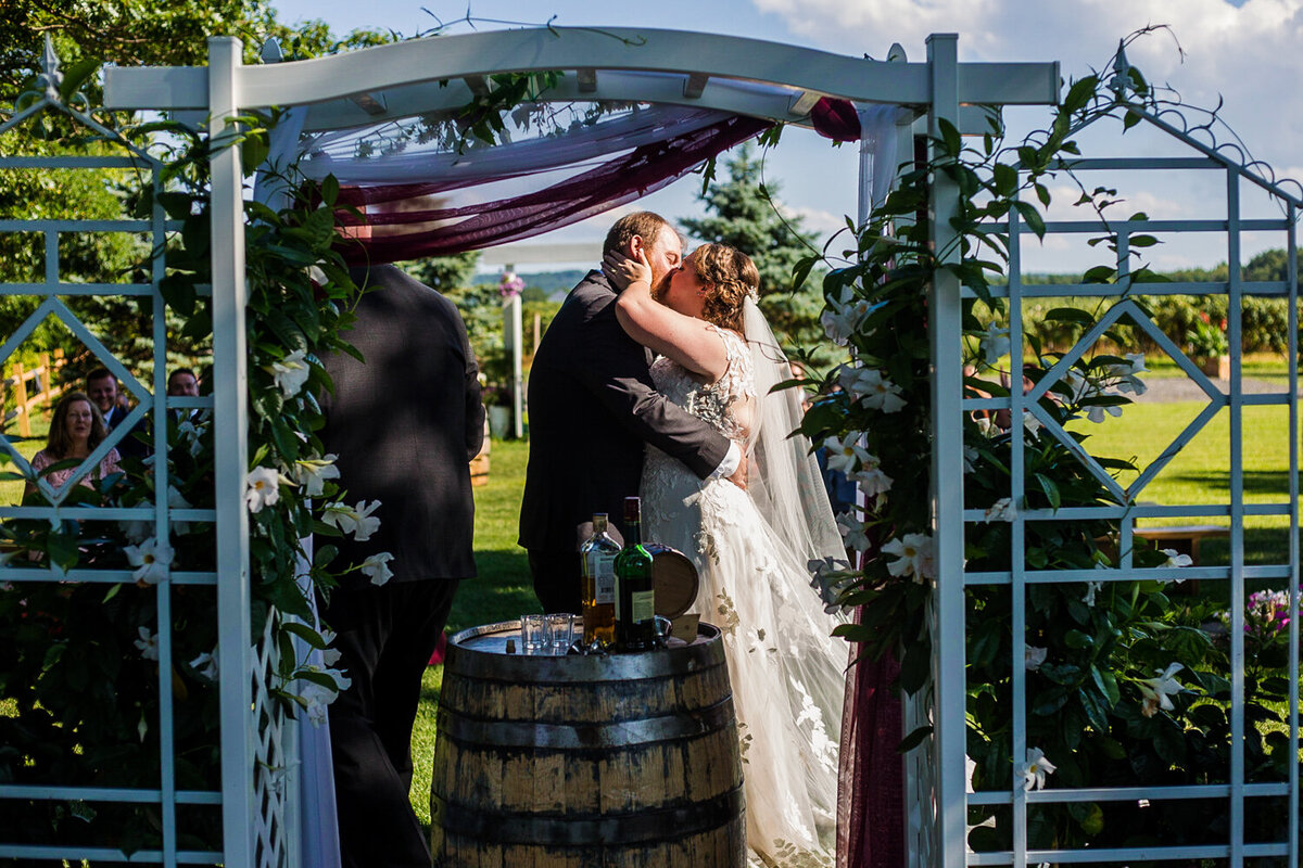 Bride and groom share first kiss at the end of their Lakeshore Vineyard wedding ceremony in Ripley NY
