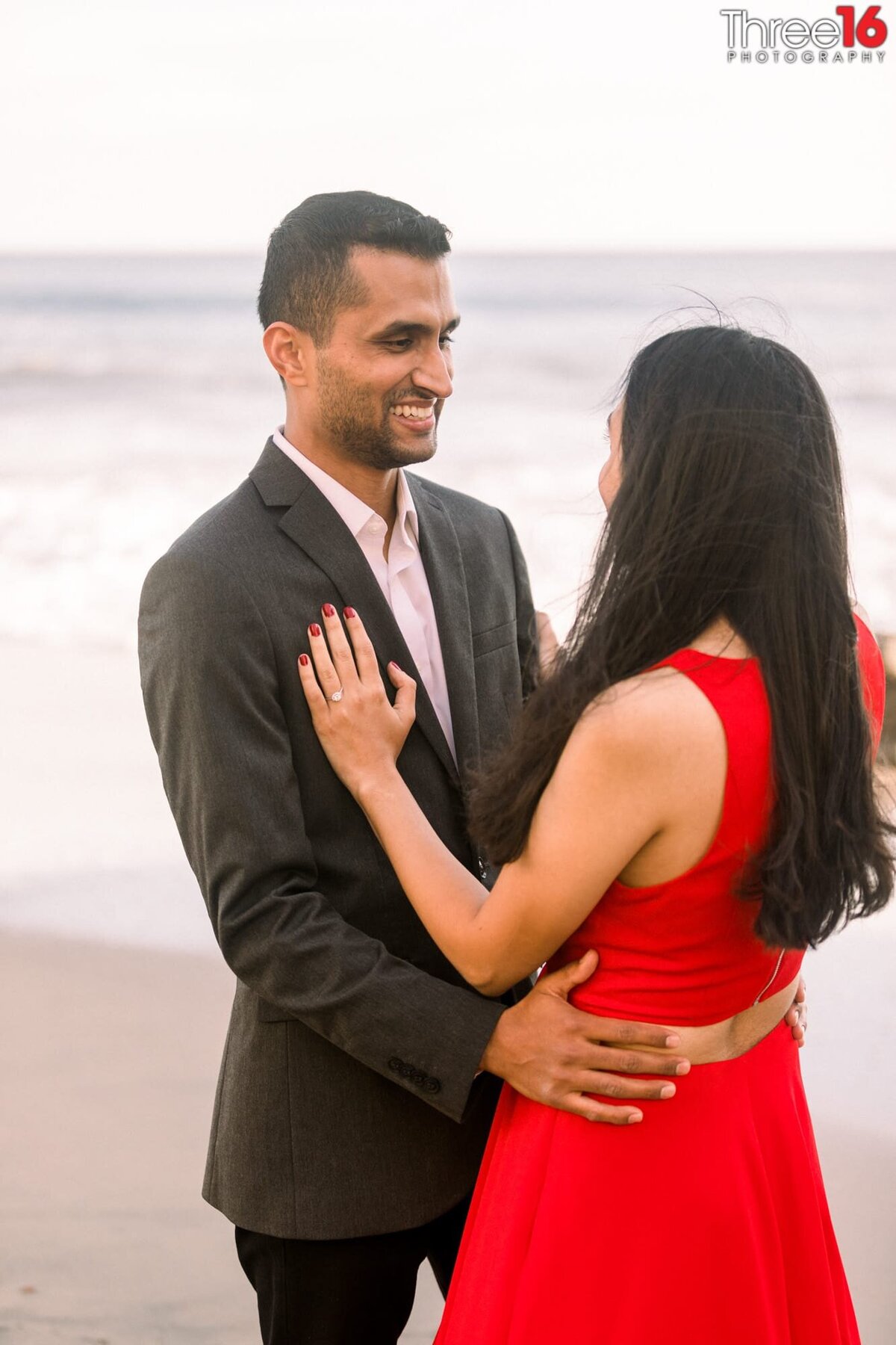 Newly engaged couple hold each other and smile at one another after the proposal