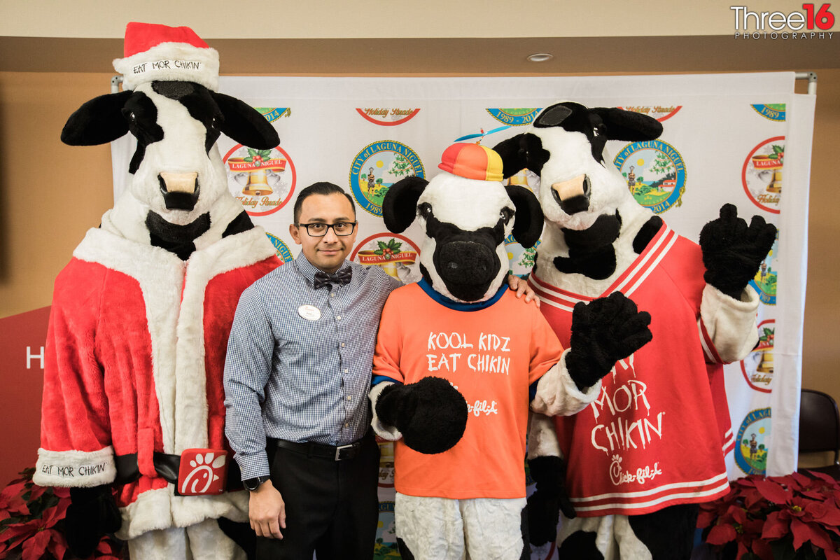 Member of Chick-Fil-A poses with company cow mascots