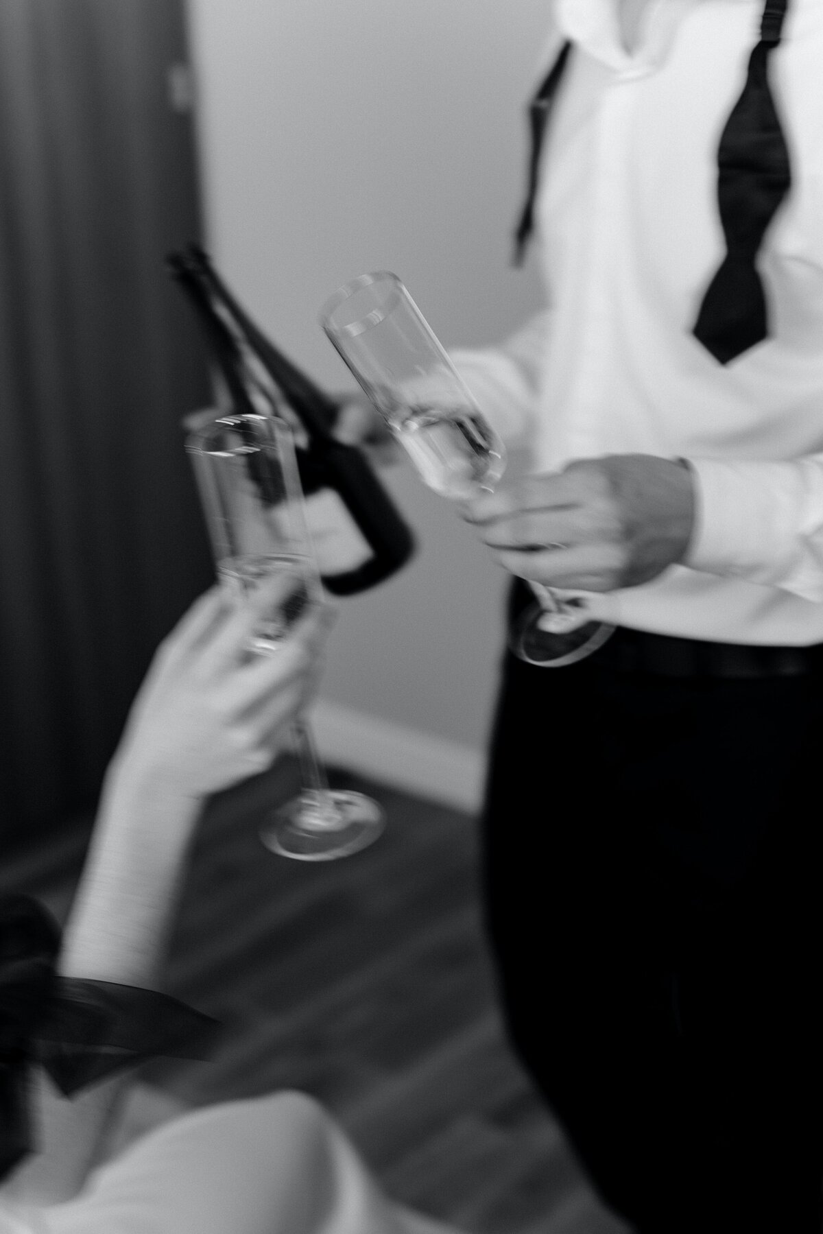 A blurred image of two champagne glasses as people are reaching in to clink them together.