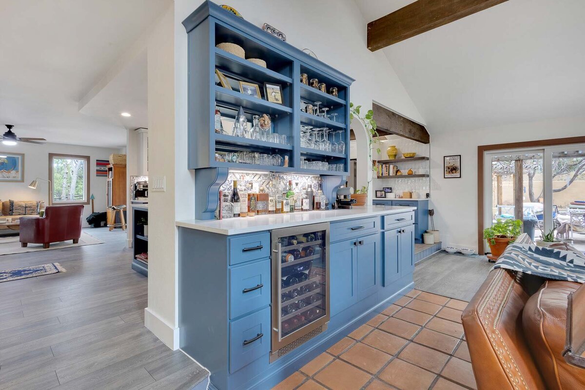Blue cabinets and shelfs holding glasses and decor, built between two doorways.