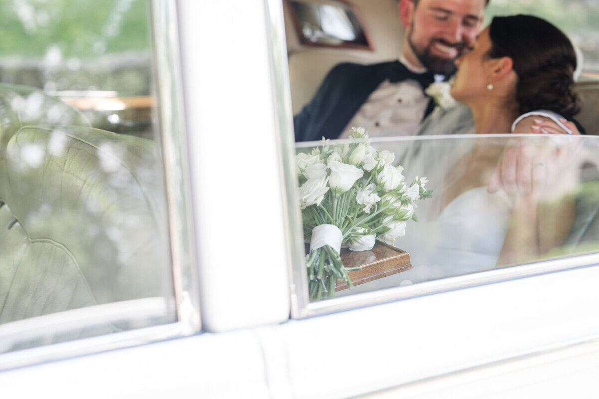 Bride and groom in a car with flowers after wedding in Cincinnati, photographed by Courtney Rudicel