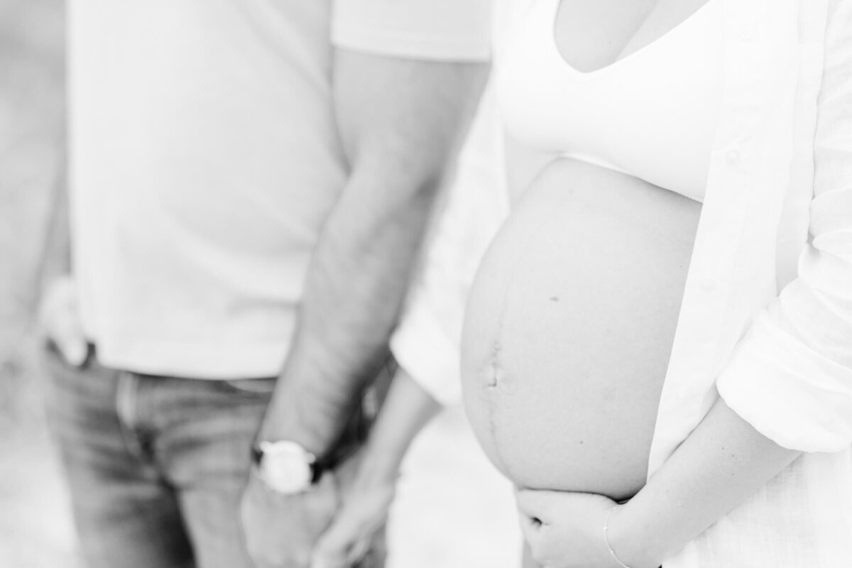 Soft focus image of a mom with a bare baby bump walking with her husband