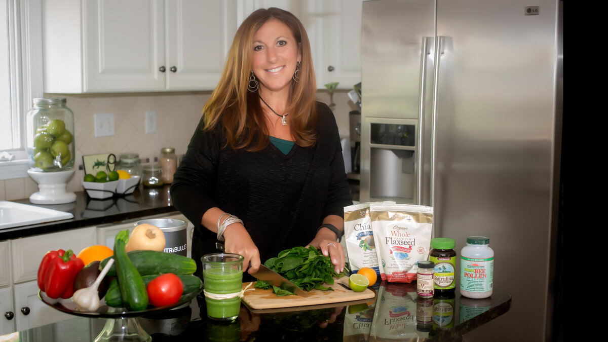 Female branding client standing in her kitchen preparing a meal for her nutrition business while posing for a South Shore MA branding photographer