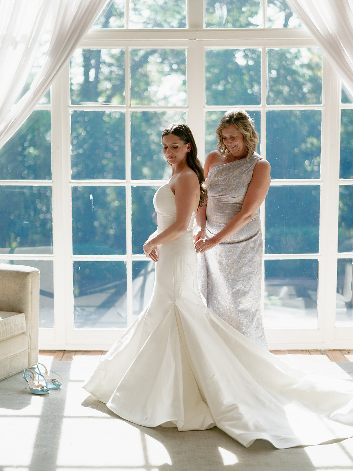 bride getting dressed with mother of the bride