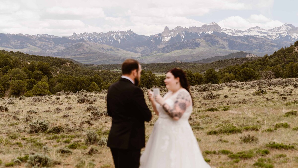  Bride and groom stand facing each other during their Ridgway State Park wedding with sweeping mountain views in the background.
